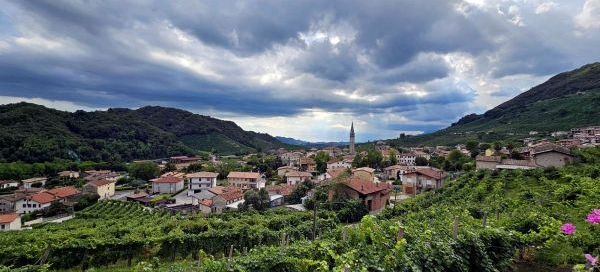 Imaginea prezintă peisajul pitoresc al zonei Valdobbiadene, renumită pentru podgoriile sale și vinur.